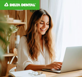 A women sitting at her desk working on her computer with a big smile on her face